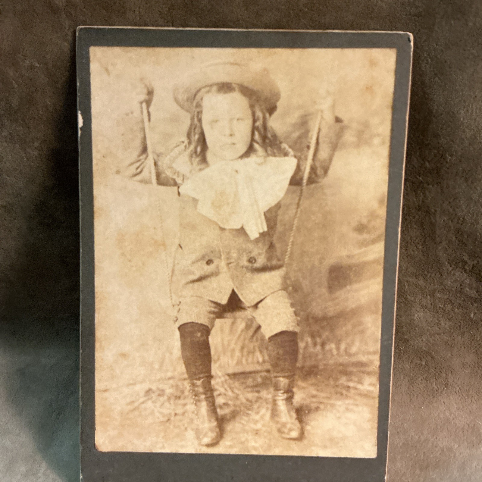Victorian 1880s photograph boy on swing with long hair big bow disappointed look