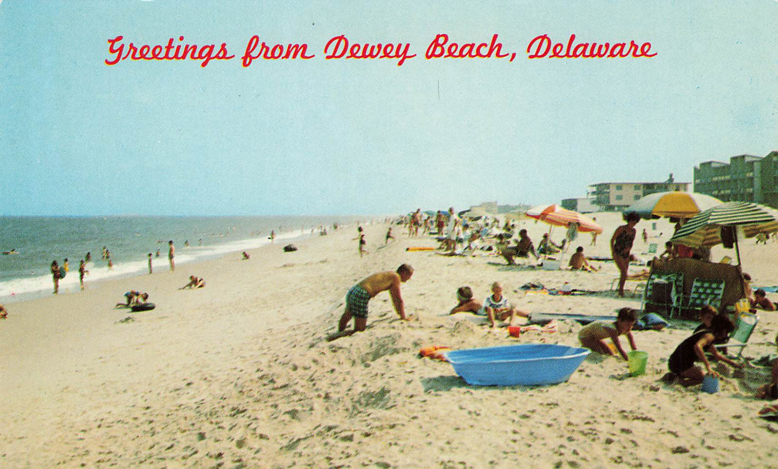 PLAYING ON BEACH SUNBATHERS GREETINGS POSTCARD DEWEY BEACH DE DELAWARE 1960s
